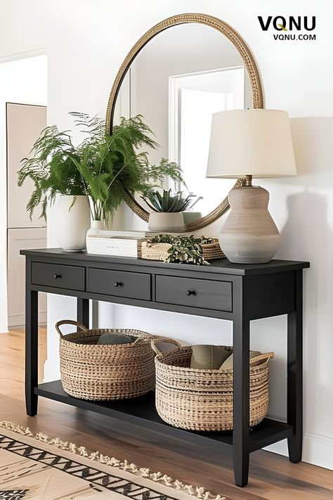 Elegant entryway with a black console table, round mirror, green plants, woven baskets, and a stylish table lamp. Entryway With Black Table, Hallway With Console Table, Black Sideboard Entryway, Hallway Entry Table, Entryway Sideboard Decor, Round Mirror Entryway Decorating Ideas, Hallway Sideboard Ideas, Hallway Console Table Ideas, Black Entry Table Decor