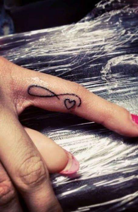 50 Powerful Infinity Tattoo Designs & Meaning - The Trend Spotter Infinity Love Tattoo, Tattoo For Women Small, Ears Tattoo, Inner Finger Tattoo, Infinity Tattoo With Feather, Heart With Infinity Tattoo, Heart Tattoo On Finger, Kids Ring, Tattoo Finger