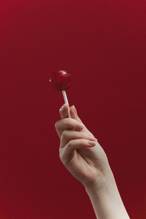 A Hand Holding a Lollipop Near Red Background · Free Stock Photo Hand Holding A Lollipop, Holding A Lollipop, Product Photography Inspiration, Hand Held Food, Food Product Photography, Candy Drawing, Red Lollipop, Lock Screen Wallpaper Iphone, Happy New Year Images