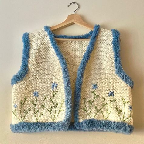 This image shows a crocheted vest with an open front. It is bone white in color and it was made with the moss stitch which gives it an incredibly textured look. The edges are lined with fluffy muted dark blue fur-like material. The body of the vest has embroirdered flowers on it. Diy Crochet Vest, Waistcoat Design, Waistcoat Designs, Crochet Waistcoat, Sewing Templates, Crochet Case, Crochet Fairy, March 9th, Design Clothes