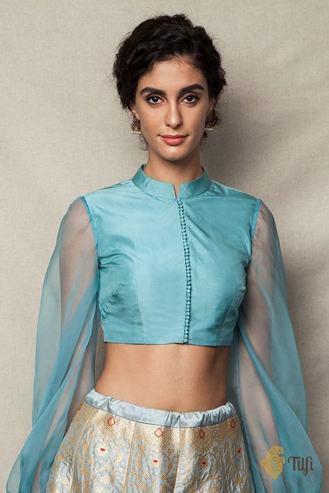 "Whimsical and absolutely fun! This a beautiful and dainty blouse in pure silk with delicate balloon sleeves in pure organza. A chic neckline and a delicate line of fabric buttons makes for a feminine and fabulous saree accent.\n\n\n Color - A beautiful shade of light Blue\n\n Fabric - Pure Katan Silk body and pure Organza Silk Sleeves\nPlease allow 10-12 business days for despatch.\n\n\nSize Guide" Balloon Sleeves Blouse, Flare Blouse, Organza Blouse, Shades Of Light Blue, Stitching Dresses, Classic Blouses, Feminine Blouses, Indian Blouse, Balloon Sleeve Blouse