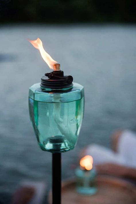 This torch features a stylish metal design & teal glass fuel vessel, a convertible 4-piece pole, a long-lasting wick & metal snuffer. This torch boasts a 12-hour burn time as well as our innovative new adjustable flame. This versatile torch transforms from a 65-inch full-sized torch to a 50-inch garden torch. Torches Tiki, Garden Torch, Backyard Celebration, Outdoor Torches, Steel Barrel, Tiki Torches, Glass Canisters, Deck Lighting, Mosaic Garden