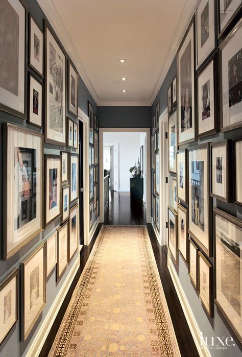 A peek to the foyer from the grand staircase. The custom bronze balustrade and mahogany handrail were custom by interior designer Neal Beckstedt. Art Display Home, Photo Gallery Hallway Ideas, Basement Hallway Decor, Hallway Of Pictures, Long Hallway Picture Wall Ideas, Ancestry Wall Display, Splurge Vs Save Home Decor, Long Hallway Art, Gallery Hallway Ideas