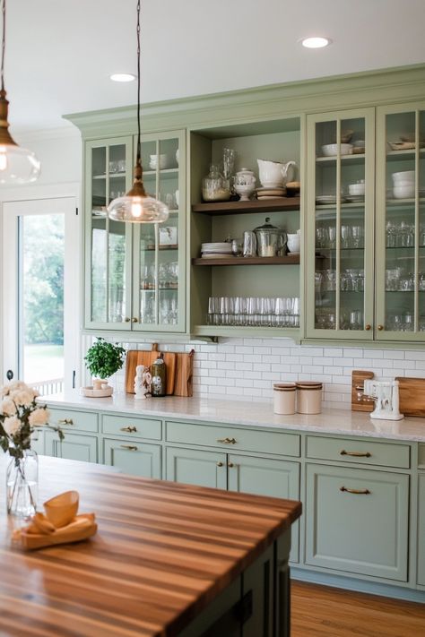 Modern kitchen with sage green cabinets, glass doors, and a wooden island countertop. Devol Kitchens Green, Painted Cottage Cabinets, Cottagecore Kitchen Remodel, Century Home Kitchen, French Inspired Kitchen, French Provincial Kitchen, French Style Kitchen, Cottagecore Kitchen, Bungalow Kitchen