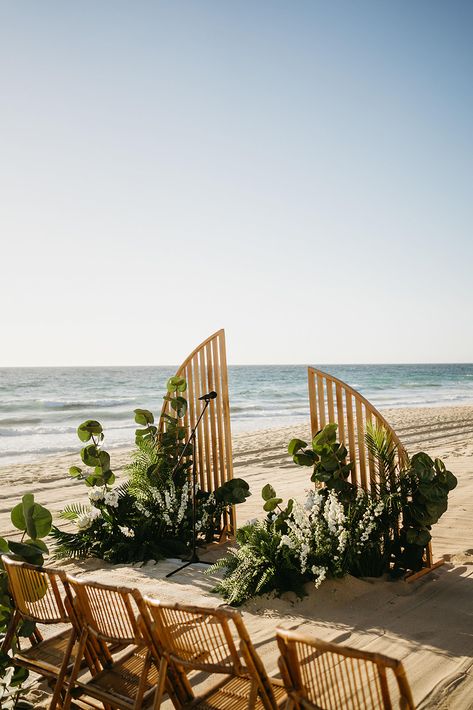 This minimalist, wooden arch paired with lush greenery and tropical florals sets the perfect scene for a beachfront ceremony at Villa Santa Cruz in Todos Santos. Ideal for couples looking for a modern, natural look that complements the ocean backdrop. The simple lines and organic design add a touch of elegance to this unique beach wedding setup. #VillaSantaCruzWedding #BeachCeremonyArch #TodosSantosWedding #MinimalistWeddingDecor #BeachfrontWeddingInspo Tropical Ceremony Decor, Tropical Backdrop Wedding, Beach Ceremony Arch, Tropical Minimalist Wedding, Hawaiian Wedding Decor, Minimalist Tropical Wedding, Unique Beach Wedding Ideas, Minimalist Beach Wedding, Elegant Tropical Wedding