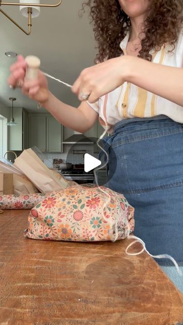 Sarah on Instagram: "Mother’s Day loaf wrapping, but make it floral!   Wearing my @ballerinafarm apron! Love it so much 🤎  #microbakery #sourdoughmicrobakery #organicmicrobakery #homestead #sustainable #sourdough #organicbread #organicgoods #bread #ovenspring #shaping #organicsourdough #baguette #organicbaguette #shaping #breadshaping #farmhouse #farm #homestead #ovenspring #puttingthebreadtobed #slowliving #bakeryviews #slowdown  #mothersday #gifting" Artisan Bread Wrapping Ideas, How To Wrap Bread As A Gift Basket Ideas, Apron Gift Wrapping Ideas, Bread Gift Wrapping Ideas, Packaging Bread Loaf, How To Gift Homemade Bread, How To Wrap Bread Loaf, Gift Wrap Sourdough Bread, Sourdough Bread Gift Basket Ideas