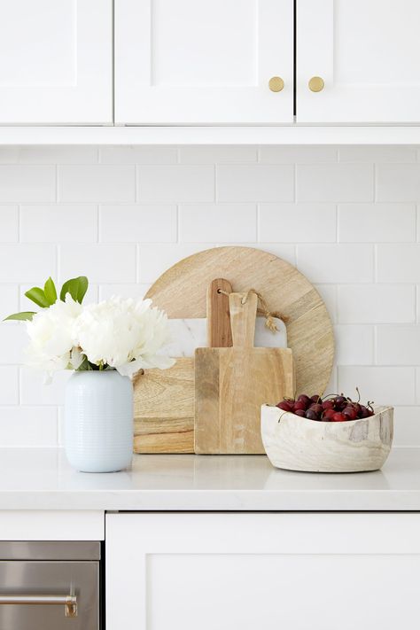 white peonies with wooden chopping boards in white shaker kitchen with brass hardware Counter Top Styling, Wooden Benchtop Kitchen, Wood Kitchen Accessories, Brass Kitchen Hardware, Kitchen Decor Styles, Natural Wood Kitchen, Kitchen Countertop Decor, White Shaker Kitchen, Wood Chopping Board