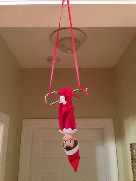 Elf on the shelf - Elfie hanging from a candy cane swing Elf Hanging From Light, Elf On The Shelf Hanging From Ceiling, Elf On The Shelf Hanging From Fan, Elf On The Shelf Candy Cane, Elf On The Shelf Hanging Ideas, Elf On The Shelf Candy, January Home Decor Ideas, Elf Idea, Giant Candy Cane