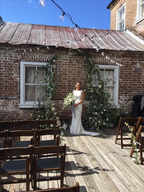 Greenery arch backdrop against brick wall for wedding ceremony in Charleston, SC. Flowers by Purple Magnolia. Intimate Wedding Backdrop, Eloped Pictures, Brick Wall Wedding Backdrop, Wall For Wedding, Greenery Arch, Purple Magnolia, Wedding Ceremony Decorations Outdoor, City Backdrop, Outdoor Backdrops