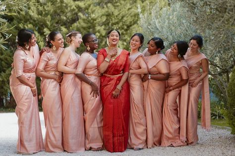 Bridal party with bride in a red lehenga and pink bridesmaids dresses Red Saree Bride With Bridesmaid, Indian Bridesmaids Saree Outfits, Indian Bridesmaid Gifts, Telugu Bridesmaids Outfits, Pink Bridesmaid Saree, Bridesmaid In Saree, Tamil Wedding Bridesmaid, South Indian Bridesmaids Saree, Tamil Bridesmaid