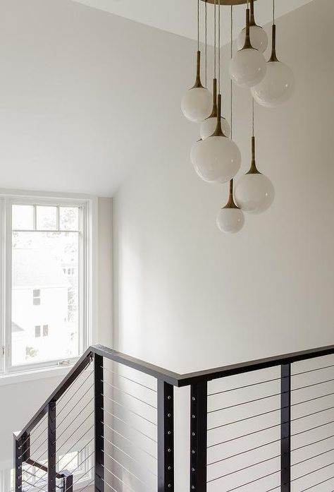 Iron black staircase brings a contemporary and sleek design around white walls. Staircase Chandelier Contemporary, Stair Lighting Pendant, Stairway Chandelier, Staircase Pendant Lighting, Staircase Lighting Ideas, Black Staircase, Ski House Decor, Stairwell Lighting, Lights Room