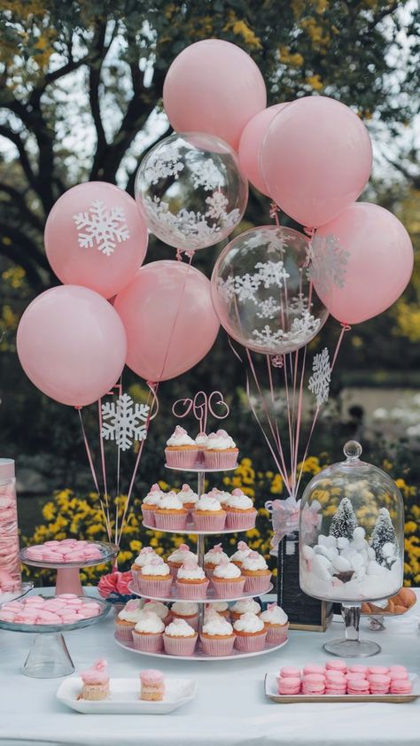 Winter Onederland dessert table with pink frosted cupcakes, macarons, and a snowy cloche centerpiece, surrounded by pink and clear balloons adorned with snowflakes for a festive birthday celebration. Winter Princess Party, Pink Winter Birthday Party, Winter Theme Food Ideas, Onederland Food Ideas, First Birthday Table, Snow Birthday Theme, Pink Winter Onederland Party, 2nd Birthday Party For Girl Winter, Onederland First Birthday