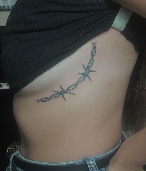 barbed wire tattoo around the side of the breast Spine Tattoos Barbed Wire, Barbed Wire Women Tattoo, Longhorn Barbed Wire Tattoo, Barbed Wire Rib Tattoo, Barbed Wire Hip Tattoo, Thigh Barb Wire Tattoo, Western Tattoos For Women Ribs, Western Barbed Wire Tattoo, Barbwire Tattoo Around Thigh