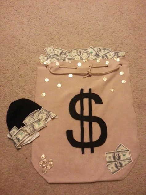 Money bag infant costume Made with fleece felt and money fabric. I made the fleese like a sack so that it was like a blanket, cut out the dollars from money fabric,  coins from a spoll of yard that had coins on it. We dressed in all black with bennies and pinned the cut out dollars in random places on pur clothe to look like theives. Money Bag And Robber Costume, Bag Of Money Costume, Money Bag Costume, Shirt Made Out Of Money, Purse Made Out Of Real Money, Money Costume, Baby Carrier Costume, Money Sack, Robber Costume