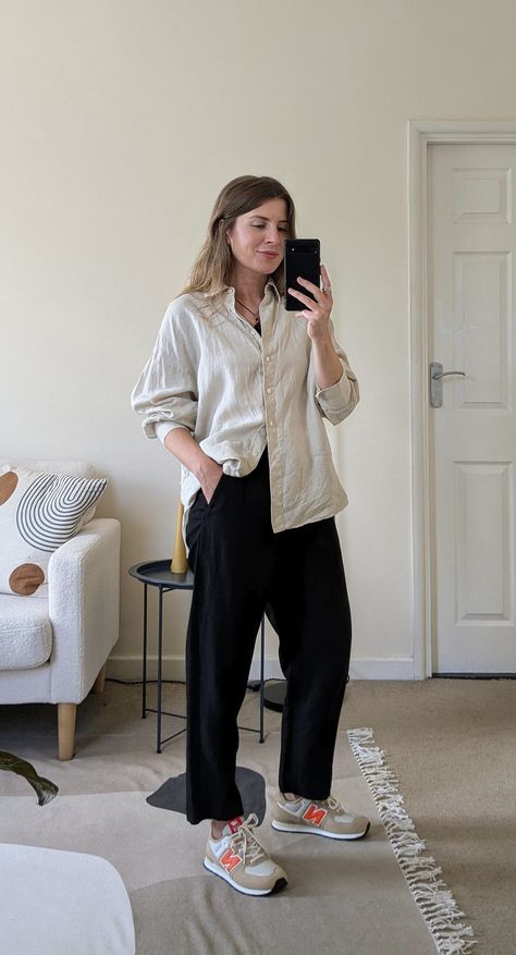 A woman stands in front of a mirror. She wears a black cord necklace, ecru oversized shirt with the sleeves pushed up, black cropped trousers and beige and orange New Balance sneakers. Crop T-shirt Outfits, Women’s New Balance 574 Outfit, Oversized Outfits Summer, New Balance Work Outfit, Cute Outfits With New Balance, Casual Summer Outfits With Sneakers, Black New Balance Outfit, New Balance Outfit 574, Outfits With New Balance Shoes