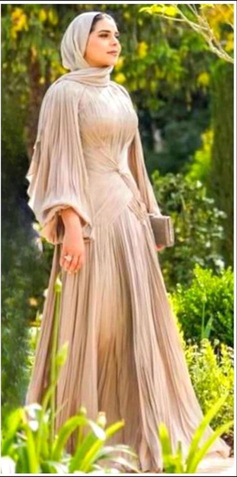 Woman in a hijab wearing a gold pleated dress with big sleeves, full skirt and a tie in the front Wide Dresses Hijab, Hijabi Prom Dress Classy, Gold Dress Hijab, Soiree Dresses For Hijab, Hijab Business, Gold Dress Outfits, Hijabi Gowns, Royal Gowns, Hijab Wedding Dresses