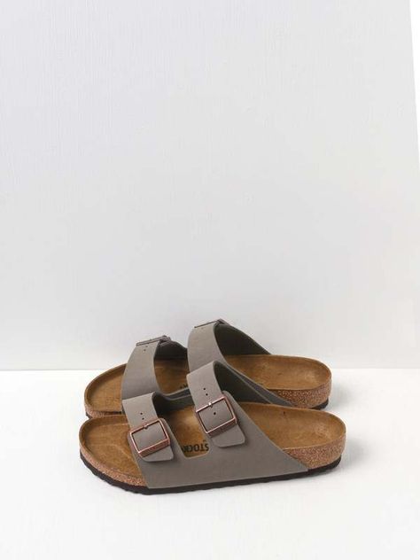 Our iconic two-strap style, the Arizona, is known for being the epitome of comfort. Both straps have buckles for a fantastic fit. Offered in classic footbed in Stone Birkibuc. Made in Germany. Composition&Care - Upper material: Birkibuc - a synthetic material made of acrylic and polyamide felt fibers that is comfortable and tear-resistant. This material offers a textured finish that looks and feels like velvety nubuck. Wipes clean with mild soap and water. - Footbed: The classic Birkenstock footbed - features pronounced arch support, a deep heel cup, and a roomy toe box. The footbed conforms to the shape of your foot. - Sole material: EVA - flexible, lightweight, durable and shock absorbing. Designer - by Birkenstock - Product ID: 250183951 - Style#: 151211 Birkenstock Arizona Stone, Stone Birkenstock, Pumped Up Kicks, Birkenstock Sandals, Closet Essentials, Shape Of You, Synthetic Materials, Birkenstock Arizona, Lifestyle Shop