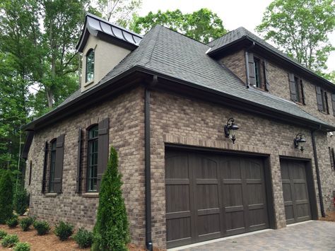 ARH Asheville 1131F Plan (Exterior 40) Stone: Oakridge (gray mortar), Brick: Boral Bastille, Room: Grand Manor Tudor Brown, Metal Roof: Dark Bronze, Soffits/Fascia/Trim: SW7020 Black Fox, Stucco: #210 London White, Window Frames: SW7038 Tony Taupe, Shutters/Columns/Cedar Brackets: SW3001 Shagbark, Entry Porch: Crab Orchard Brown, Front Door/Garage Door Stain: SW3518 Hawthorne, Rear Porch Flooring: Daltile Ayers Rock Majestic Mound (Grout #165 Delorean Gray) Brown Brick Exterior, Brown Garage Door, Brown Brick Houses, Log Homes Exterior, Grey Exterior House Colors, Gray House Exterior, House Exterior Colors Schemes, Brown Brick, Garage Door Design