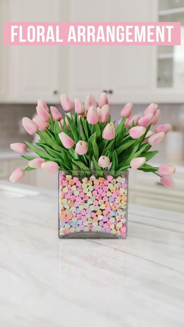 Brittany | Home Decor & Style on Instagram: "Valentine’s Floral Arrangement using faux flowers from @amazon 🌸 These faux tulips look and feel real. I’m using a total of 40 tulips here, two cube vases from Michael’s, and sweetheart candies from Walmart 💗 LINK IN BIO TO SHOP or shop LikeToKnow.it/FiveFootFeminine 💗 #valentinesdecor #flowerarrangement #flowerarrangements #floralarrangement #floralarrangements #amazonfinds #founditonamazon" Sweetheart Candies, Vase Filler Ideas, Faux Tulips, Valentine Sweets, Valentine Flower Arrangements, Sweetheart Candy, Candy Arrangements, Valentines Snacks, Tulips Arrangement