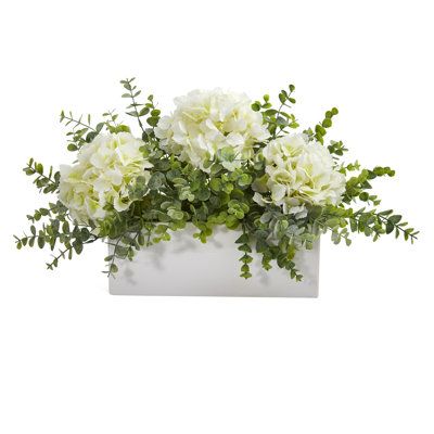 Incorporate hints of countryside beauty with the help of this artificial arrangement flaunting a collection of realistic looking silk hydrangea blossoms, each intricately designed in soft, subtle colors and highlighted throughout with an overgrowth of eucalyptus foliage in complementary green hues. Resting 15in. wide in a white vase, this incredibly lifelike arrangement evokes elegant beauty wherever displayed. About Gracie Oaks Inc. - For over 75 years, Gracie Oaks Inc. has been providing consc Hydrangea Flower Arrangements, Rectangular Vase, Spring Flower Arrangements, Hydrangea Arrangements, Unique Flower Arrangements, Silk Hydrangeas, Wedding Floral Centerpieces, Artificial Hydrangeas, Floral Arrangements Diy