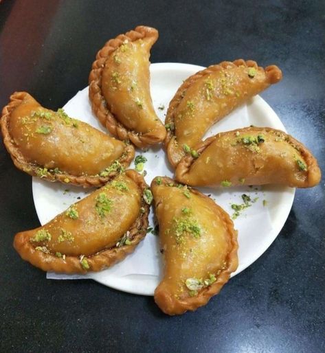 Gujiya, Gughara, Pedakiya, or karanji is a sweet deep-fried dumpling, native to the Indian subcontinent, made with suji or maida stuffed with a mixture of sweetened khoa and dried fruits, and fried in ghee. The preparation method of a typical gujiya/pedakiya is rather similar to that of a samosa, but the gujiya/pedakiya looks like an empanada. Shaped like a half moon, the gujiya or pedakiya is filled with a sweet mixture of grated and roasted dried fruits, khoa, grated coconut. Sweet Samosa, Indian Subcontinent, Tandoori Masala, Grated Coconut, Samosa, Catering Services, Dried Fruits, Sharjah, Ghee