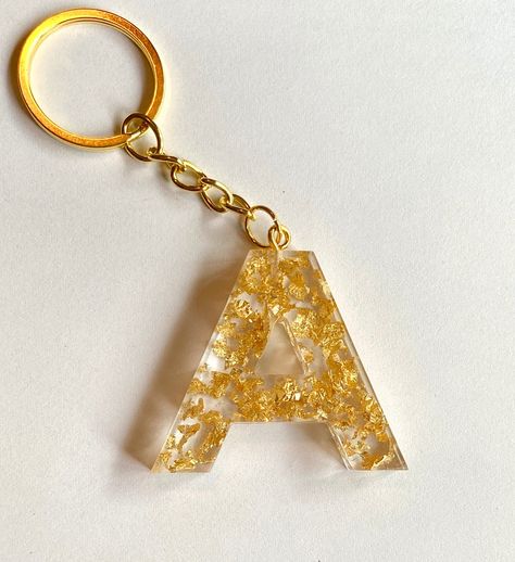 "Beautiful, meticulously handcrafted \"A\" keychain made with epoxy resin. Each metallic flake individually placed with care. Lightweight and simple. Perfect accessory to add to keys, wallets, purses, lanyards, and so much more! Creative way to reflect one's personality and makes for great gifts and party favors. Smooth to the touch. Transparency allows light to shine through and reflect radiantly against the metallic flakes.  Initial itself is 1.5 inches in length, while keychain adds additiona Resin Arts, Gold Flake, Resin Keychain, Diy Keychain, Gold Flakes, Mica Powder, To Shine, Alcohol Ink, Resin Crafts