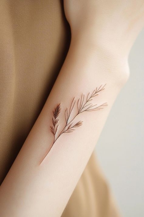 Delicate botanical tattoo on an arm featuring slender leaves and stems. Brown Tattoos For Women, Brown Ink Tattoo, Unique Small Tattoo Ideas, Brown Tattoos, Small Tattoo Design, Brown Tattoo Ink, Small Compass Tattoo, Small Mountain Tattoo, Brown Tattoo