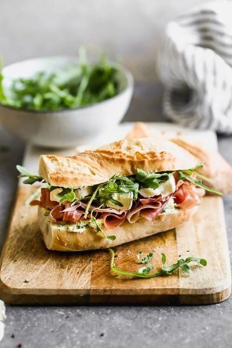 This classic French Baguette Sandwich, also known as a Jambon Beurre Sandwich is such a nice departure from a classic deli sandwich. Our version is layered on a crusty French baguette with salty prosciutto, an easy herbed butter, creamy brie, and peppery arugula. Effortlessly elegant, and most importantly, so delicious. French Baguette Sandwich, Party Subs, Sandwich Platters, Brie Sandwich, Herbed Butter, French Sandwich, Baguette Sandwich, Deli Sandwiches, French Baguette