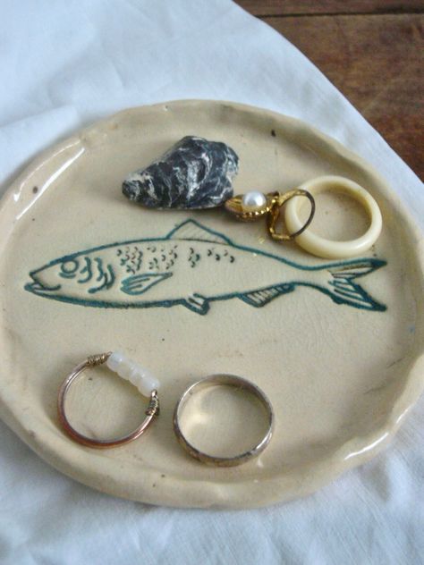 Fish decorative plate handmade in France made with clay, glazed and fired in 1050 degrees Celsius  A small decorative plate with a fish. Hand-sculpted and glazed with natural colours. Perfect for storing your rings, jewellery, keys or trinkets or as a gift. Can also be used for serving small snacks or as a soap dish. Only one piece available. Size: Diameter: around 10.5 cm (4.13 inches) IMPORTANT: Please, when buying an item, include your phone number and e-mail address in an Etsy message! These Ring Dish Pottery, Fish Ceramics Pottery, Clay Jewelry Plate, Clay Ceramics Ideas, Clay Jewellery Holder, Ceramic Ring Holder, Clay Fish, Clay Plates, Trinket Holder