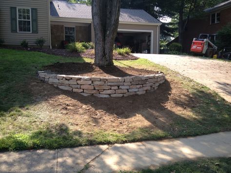 First phase of building a semi-circle tree wall please feel free to comment or ask questions! If you love this picture please follow me here on Pinterest to stay updated! Also look at my Youtube on here and subscribe to my channel! Thank you Retaining Wall Around Tree On Slope, Decor Around Trees Front Yards, Rock Wall Around Tree, Tree Retaining Wall Ideas, Retaining Walls Around Trees, Semi Circle Retaining Wall, Tree Surround Ideas Landscaping, Semi Circle Flower Bed, Tree Circle Landscape