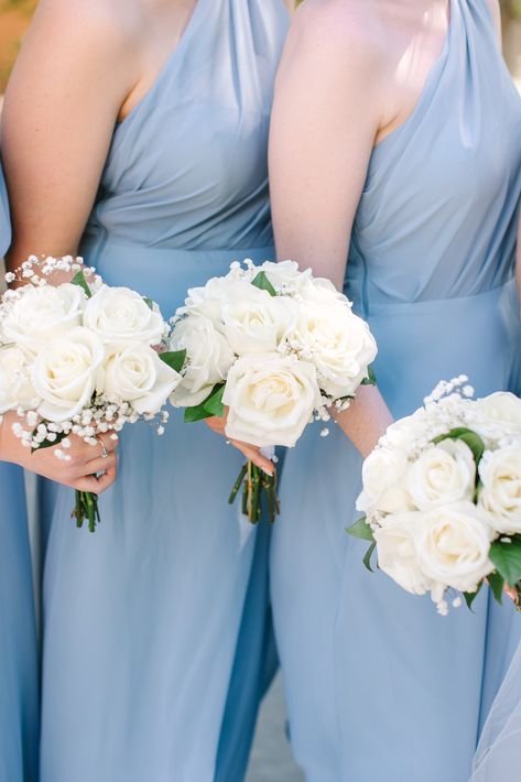 Bridesmaids are wearing light blue dresses while holding white flower bouquets. Simple White Bride Bouquet, White Flowers For Bridesmaids, White Flowers Bridesmaid Bouquet, Petite Rose Bouquet, Bridesmaid Floral Bouquet, Bridesmaid Bouquet Ideas Simple, Wedding Bouquets With Baby Breath, White Wedding Bouquets Bridesmaid, Small White Bridesmaid Bouquet Simple