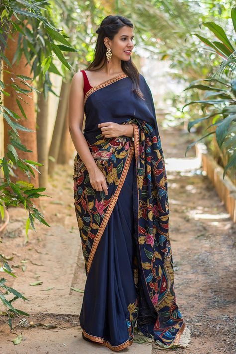 We can never get enough of Kalamkari patch works. This navy blue pure crepe beauty is an ode to our love. The brocade red border adds a touch of bling to the otherwise simple ethnic saree. The picturesque kalamkari patchwork that works a story on its own takes the saree to a different level of sophistication. Complement her with a red velvet blouse and you are sorted. ACCOMPANIMENTS: All sarees are sold completely finished with falls (where required) and a free size underskirt.  FABRIC: Sare... Navy Blue Saree, House Of Blouse, Kalamkari Sarees, Crepe Saree, Saree Blouse Patterns, Kalamkari Saree, Indian Woman, Blue Saree, Latest Sarees