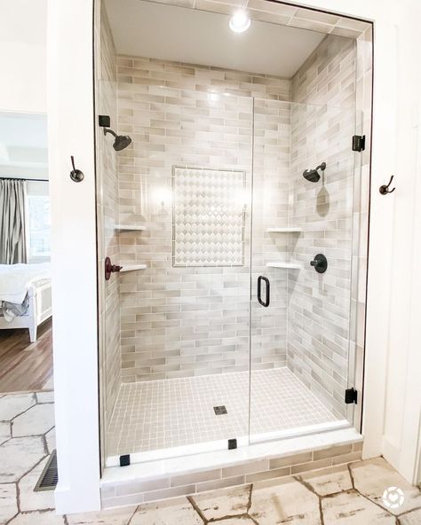 White and beige quatrefoil shower accent wall is built into a beige staggered tile shower with black hardware. White stacked corner shelves are mounted above the beige grid flooring behind the glass shower enclosure. Shower With Black Hardware, Beige Shower Tile Ideas, Beige Shower Tile, Staggered Tile, Bathroom Hardware Ideas, Shower Accent Wall, Mom Bathroom, Shower Corner Shelf, Black Bathroom Hardware