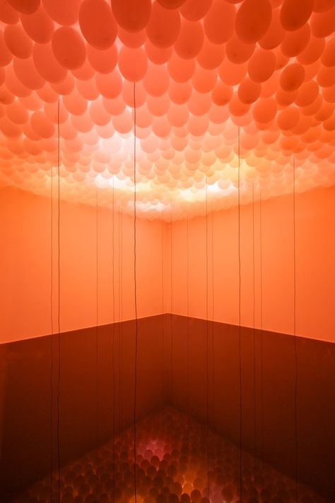 Situational Construction, a recreation of artist Lloyd Hamrol's 1969 installation, is a room that has a small window where the viewer can gaze through and see balloons taking over the ceiling. With the floor covered in still black water, it reflects the round shapes of the balloons, simulating a sunset over the sea. With hanging rods of wire that look like falling rain. Teknologi Futuristik, Popup Store, Light Art Installation, Creative Architecture, Balloon Installation, Light Sculpture, Light And Space, Art Installations, Balloon Art