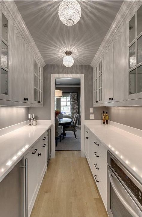 Galley style butler's pantry features a gray ceiling dotted with crystal beaded flush mounts illuminating white cabinets fitted with a stainless steel mini fridge situated across from a pull out microwave drawer. Galley Kitchen Remodel Ideas, Small Galley Kitchen, Galley Kitchen Design, Galley Kitchen Remodel, Long Kitchen, Kitchen Remodel Cost, Galley Kitchens, Narrow Kitchen, Butlers Pantry