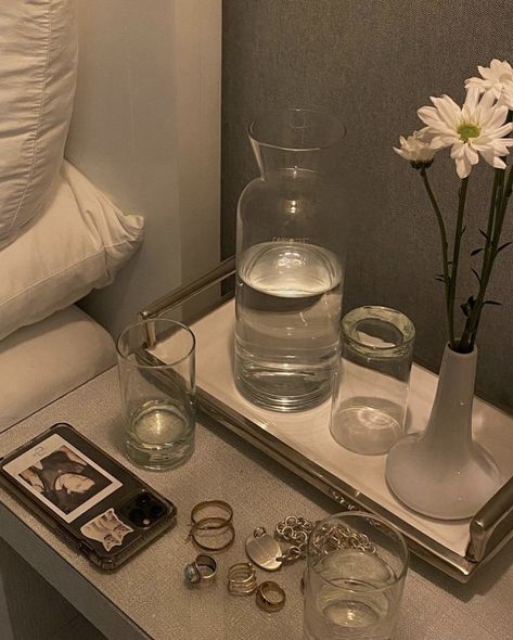 night stand photograph with water, glass, rings, white flowers, phone Night Table Decor, Eco Friendly Ideas, Light Brown Table, Bedside Table Styling, Luxury Bedside Table, Glass Nightstand, Bedside Water Carafe, Bedside Carafe, Bedside Table Decor