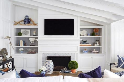 Chic living room features a sloped ceiling over a flat screen tv and white dentil fireplace mantle accented with carrera marble flanked by built-in bookshelves with backs of shelves lined with gray shiplap trim. Built In Around Fireplace, Marble Room, Fireplace Bookshelves, Shiplap Ceiling, Built In Shelves Living Room, Living Room Built Ins, Fireplace Shelves, White Shiplap Wall, Shiplap Fireplace