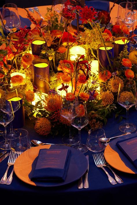 The table setting and scenography for the Guggenheim International Gala's dinner transformed the museum into a fantastical garden. Projections of flowers in an electric blue hue contrasted with the warmly lit tables for a colorful display of lights. From an aerial view, the Dior Maison table settings give the illusion that they are flowers themselves with illuminated centerpieces. © Reed Young 70th Birthday Decorations, Blue Centerpieces, Rock N Roll Wedding, Gala Ideas, Gala Party, Orange Table, Dinner Party Table, Dinner Table Decor, Dinner Decoration