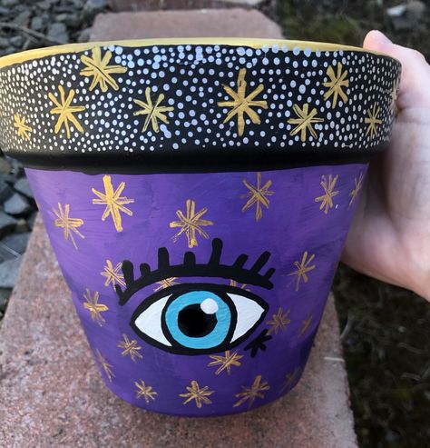 Hand painted flower pot. Acrylic Paint. Star pot. DIY. Easy painted flower pot. All seeing eye. Painting ideas. Terra cotta pots. Purple flower pot. Purple Painted Pots, Eye Painting Ideas, Painting Pots Ideas Easy Diy, Hand Painted Pots Diy, Hand Painted Flower Pots, Paint Garden Pots, Hand Painted Pots, Painted Flower Pot, Terra Cotta Pot Crafts Diy