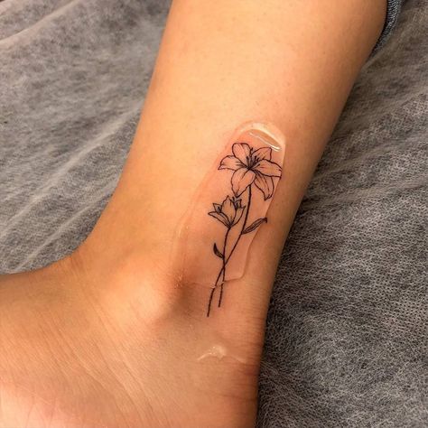 Fine Ankle Tattoo, Lily Flower Tattoos Ankle, Fine Line Flower Tattoo Matching, Lily Flower Line Tattoo, Lily Flower Tattoos Behind Ear, May Lilly Flower Tattoo, Orange Lily Tattoo Small, May Lilly Tattoo, Surprise Lily Tattoo