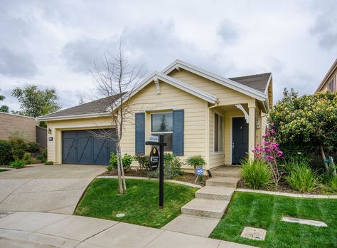 Great curb appeal wuth this house-pale yellow, white trim, blue front anf garage door, attractive landscaping Wooden Shutters Exterior, House Shutter Colors, Yellow Brick Houses, Yellow House Exterior, Exterior Garage Door, Tan House, Exterior Color Palette, Townhouse Exterior, Ranch House Exterior