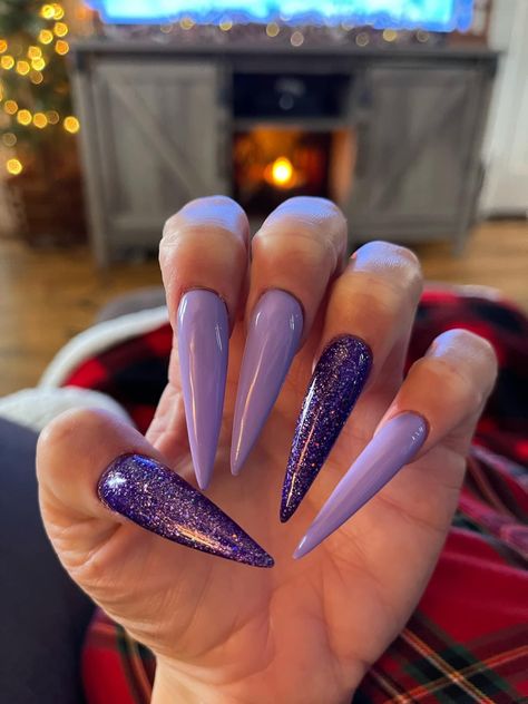 White hand with long purple stiletto shaped nails. Light purple and dark purple glitter. Dark Purple Acrylic Nails Design, Purple Nails Long, Purple Stilleto Nails, Purple Nails Stiletto, Purple Stilletos Nails, Purple Stiletto Nails Design, Dark Purple Glitter Nails Acrylic, Staleto Nails, Purple Spring Nails