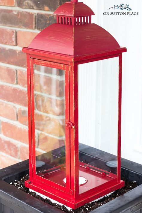 Christmas Lantern Ideas Front Porches, Outdoor Lantern Christmas Decor, Large Lantern Christmas Decor Ideas, Xmas Porch Decorating Ideas, Red Christmas Lanterns Decorating Ideas, Christmas Planter With Lantern, Simple Christmas Lantern, Porch Lanterns Decor, Outdoor Lantern Ideas