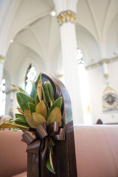 a magnolia leaves arrangement with a brown ribbon bow for the aisle decor Winterthur Wedding, Chapel Flowers, Southern Wedding Decorations, Ceremony Space Decor, Fresh Wedding Bouquets, Pew Markers, Creative Wedding Centerpieces, Pew Flowers, Pew Decorations