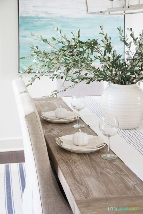 A simply fall tablescape with linen chair, reclaimed wood table, white vase, olive leaf stems, and neutral striped napkins. Coastal Dining Room, Australia House, Coastal Dining, Dining Room Remodel, Coastal Living Rooms, Beach House Interior, Coastal Living Room, Coastal Interiors, Interior Modern