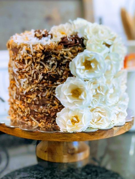 4 layer German chocolate cake, filled with chocolate buttercream and our brown sugar pecan frosting! A little toasted coconut and some fresh flowers top it all off! German Chocolate Anniversary Cake, Decorate German Chocolate Cake, German Chocolate Cake Wedding, Fancy German Chocolate Birthday Cake, German Chocolate Wedding Cake Ideas, German Chocolate Cake Designs, German Chocolate Cake Decorated, German Chocolate Wedding Cake, Chocolate Anniversary Cake