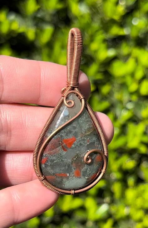 Bloodstone Copper Wire Wrapped Pendant Necklace ~ Handmade Wire Wrapped Crystals ~ Jewelry ~ Genuine stone crystal. Listing is for exact item pictured. Choose either pendant alone or included matching chain. Size Approx: 6x3cm Gemstone Type: Semi-Precious Gemstone Gift wrap optional! *Free shipping over $35 in the US* In the ancient world, Bloodstone (Heliotrope) was considered to be the most beautiful of the Jaspers, a deep, earthy green gem emboldened with spots of bright red. Called the Sun S Wire Wrapped Cabachon Pendants, How To Wire Wrap Gemstones, Small Wire Wrapped Pendant, Copper Wrapped Crystals, Mens Wire Wrapped Jewelry, Diy Wire Jewelry Tutorials, Easy Wire Wrapping Stones, Simple Wire Wrapped Pendant, Wire Wrapped Pendant Tutorial