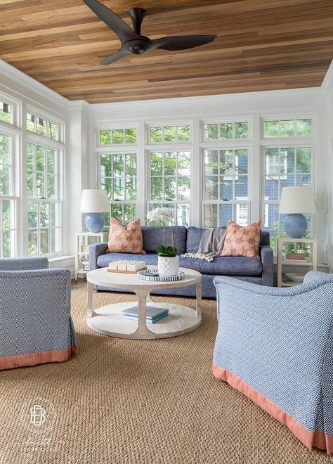 A matte black modern ceiling fan is mounted in a sunroom to a wood plank ceiling over a round gray wash wooden coffee table placed on a sisal rug. Southern Sunroom, Sunroom Ceiling Ideas, Black Modern Ceiling Fan, Traditional Sunroom, Small Sunroom, Round Rug Living Room, Wood Plank Ceiling, 4 Season Room, 3 Season Room