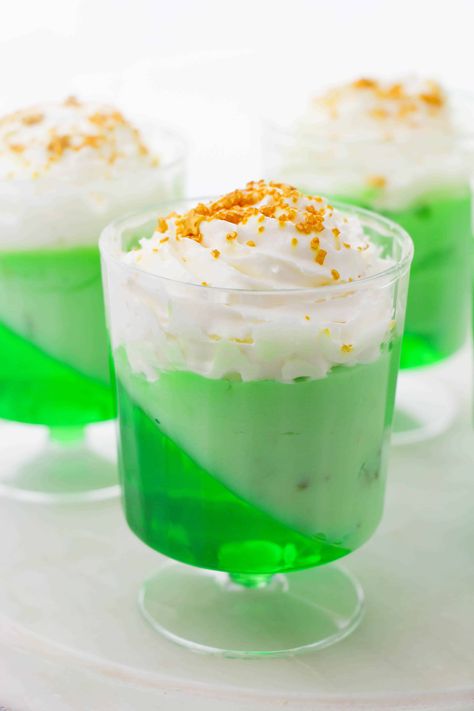 Green Jello Parfaits - these parfaits are a perfect dessert for St. Patrick\'s Day! It\'s made with a green jello and pistachio pudding. It\'s topped with whipped cream and some gold sugar on top. Green Jello Desserts, Jello Recipes Christmas, Jello Parfait, Bowl Desserts, Sant Patrick, Cups Recipes, Green Dessert, Christmas Banquet, Green Jello