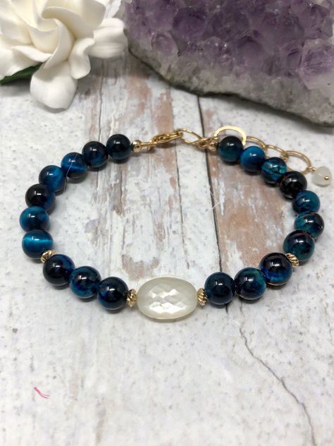 This gorgeous bracelet features AAA white moonstone. The glow that is in this gem is incredible. I have paired it with deep blue tiger’s eye that is luminous with bands of shimmer and added 14kt gold filled accents. The dark, velvety blue and shimmering, satin white are mesmerizing together. Finished with a white moonstone drop and 14kt gold filled chain. Adjustable from 6.25 to 7.75 inches. #christmasgiftideas #giftsforher #giftsfordaughter #giftsforwife #giftsforsister Blue Tiger Eye Bracelet, Green Onyx Necklace, Gold Tiger Eye, Tiger Eye Jewelry, Blue Tiger, Tigers Eye Necklace, Tiger Eye Bracelet, Beaded Jewelry Designs, Blue Tigers